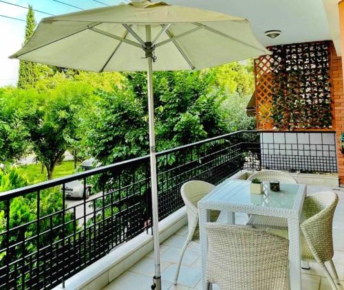 una mesa blanca y sillas en un balcón con sombrilla en URBAN LIFE STYLE en Tesalónica