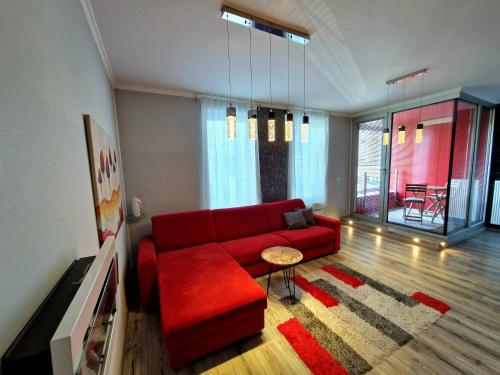 a living room with a red couch and a table at Apartmánik v tichom nádvorí - free parking in Bratislava