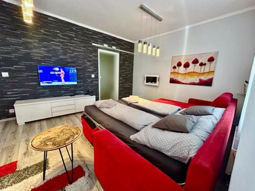 een woonkamer met een rode bank en een tv bij Apartmánik v tichom nádvorí - free parking in Bratislava