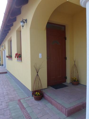 a front door of a house with two potted plants at Kiserdő Vendégház in Rajka