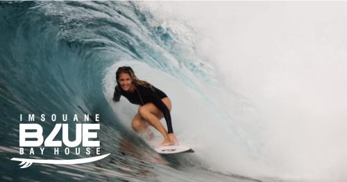 a woman riding a wave on a surfboard in the ocean at imsouane bleu bay house in Imsouane
