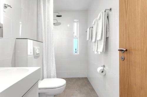 a white bathroom with a toilet and a sink at Nes Residence in Reykjavík