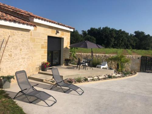 two chairs and an umbrella in a patio at L inarretable studio independant in Cubnezais