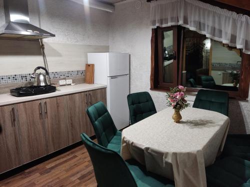 eine Küche mit einem Tisch mit grünen Stühlen und einem Kühlschrank in der Unterkunft Апартаменти "У Кузьмича" 1 in Mykulytschyn