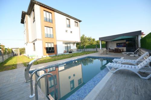 una piscina con 2 sillas y una casa en Konakönü center 1, en Trabzon