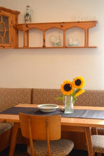 a wooden table with a vase of sunflowers on it at Gemütliche Ferienwohnung - Prein an der Rax in Prein an der Rax