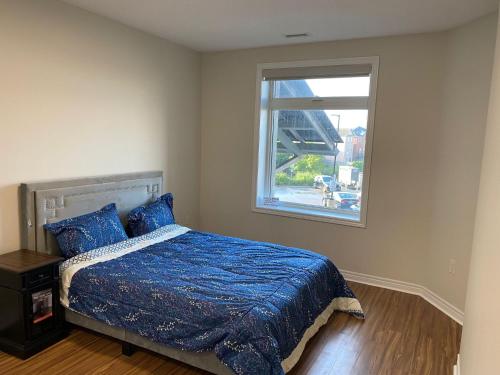 ein Schlafzimmer mit einem Bett mit blauer Decke und einem Fenster in der Unterkunft 10 The 3 Bed 2 Bath Weekend Getaway Property with Underground Parking in Markham