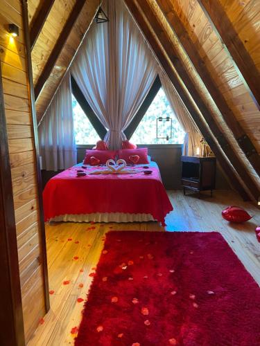 a bedroom with a red bed with a large window at Chalé São Bento - Lareira, churrasqueira e uma vista incrível para o Vale in Ibicaré