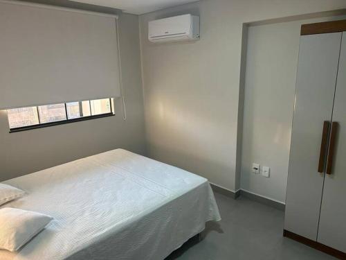 1 dormitorio con cama blanca y ventana en Apartamento aconchegante no centro de São Lourenço en São Lourenço