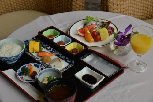 una mesa con platos de comida y un vaso de zumo de naranja en Suikouen Hotel, en Kurume