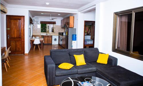 a living room with a blue couch and yellow pillows at Luxor garden apartments Accra Ghana in Accra
