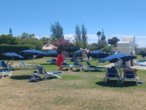 a group of lawn chairs and umbrellas in a park at Pedras D` EL Rei Village 110 in Tavira