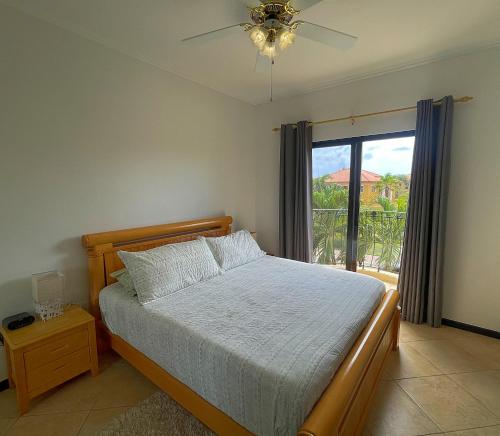 1 dormitorio con 1 cama, ventilador de techo y ventana en Diamante 242 ST Town home in Gold Coast 2 Bedrooms 3 Bath 3 Community Pools, en Palm-Eagle Beach