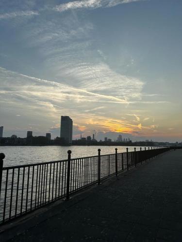 a fence next to a body of water with a city at Riverside En suite Double Room E14 in London