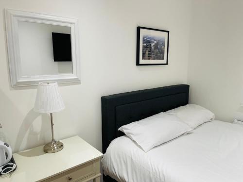 a bedroom with a bed and a table with a lamp at Riverside En suite Double Room E14 in London
