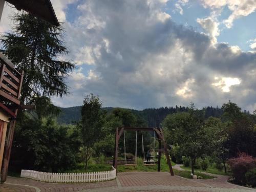 a wooden swing set in a park with trees at Апартаменти "У Кузьмича" 2 in Mykulychyn
