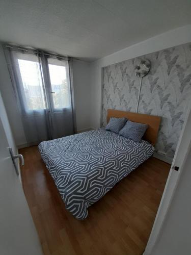 een slaapkamer met een bed met een zwart-wit dekbed bij superbe duplex avec parking gratuit in Grenoble