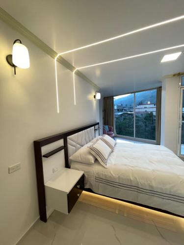 a bedroom with a bed and a large window at Hostal Balcon del Cielo in Baños