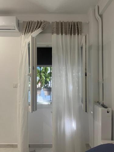 una tenda bianca in una stanza con finestra di White Apartment Athens ad Atene