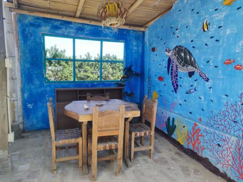 ein Esszimmer mit einem Tisch und einem Wandbild von Meeresschildkröten in der Unterkunft Guest House Villa Machalilla in Machalilla