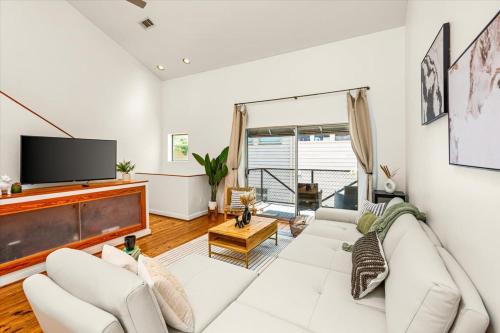 a living room with a white couch and a tv at Luxe 3 Story Townhome with Downtown View Near NRG Stadium Centrally Located Walkable To Popular Restaurants sleeps 8 in Houston