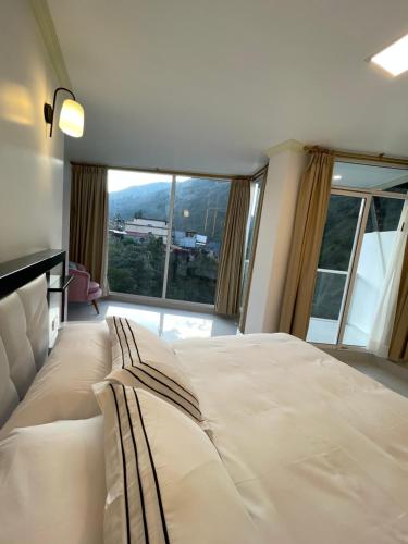a bedroom with a large bed with a large window at Hostal Balcon del Cielo in Baños
