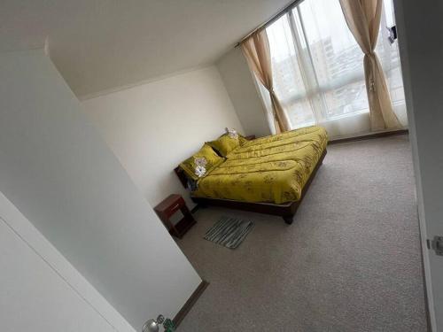 1 dormitorio con 1 cama con edredón amarillo y ventana en Excelente Departamento 2 habitaciones 2 baños Iquique, en Iquique