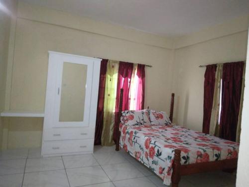 a bedroom with a bed and a dresser and a mirror at Ark Royal of the Caribbean in Arnos Vale