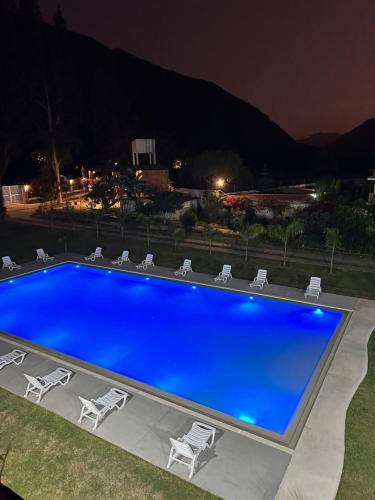 a large blue swimming pool with chairs around it at HOTEL & BUNGALOWS VILLA PALMERAS LUNAHUANA in Lunahuaná