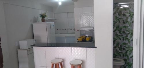 una pequeña cocina con encimera y 2 taburetes en Hospedagem Brilho do Sol, en Arraial do Cabo