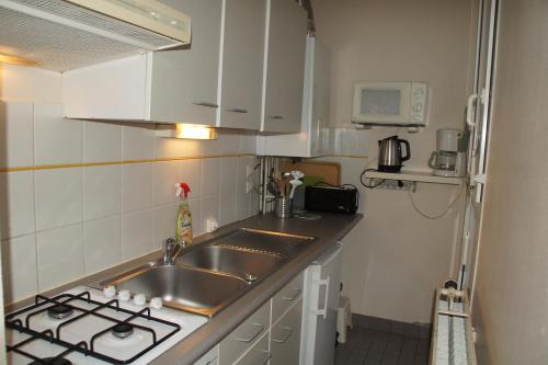 une petite cuisine avec un évier et une cuisinière dans l'établissement Thermes & Vacances Residence ATLANTICA, à Rochefort