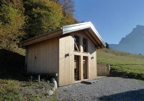 un petit bâtiment en bois sur le côté d'une colline dans l'établissement Chalet*** au pied d'une prairie face à la montagne, à Sixt-Fer-à-Cheval