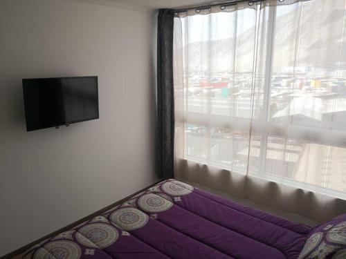 1 dormitorio con cama morada y ventana en Sensacional Departamento cerca Zofri 2 Habitaciones 2 Baños Iquique, en Iquique