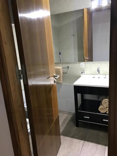 a bathroom with a sink and a mirror and a door at Departamento BLUE in San Juan