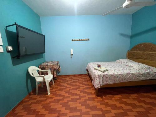 - une chambre avec un lit, une télévision et une chaise dans l'établissement HOSPEDAJE SCOMIL, à Pucallpa