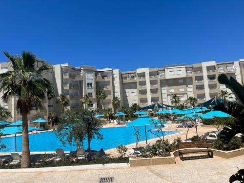 a resort with a large swimming pool with blue umbrellas at Super appartement avec 5 piscines en résidence in Monastir