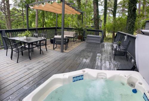 bañera de hidromasaje en una terraza con mesa y sillas en Log Cabin #2 with hot tub deck and sunset view at Loblolly Pines, en Eureka Springs