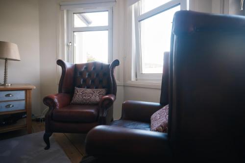 a living room with a arm chair and a chair and window at Loch Lomond Apartment in Alexandria