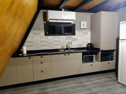 una cocina con armarios blancos y encimeras negras en Loft de Montaña Único y Moderno en Esquel