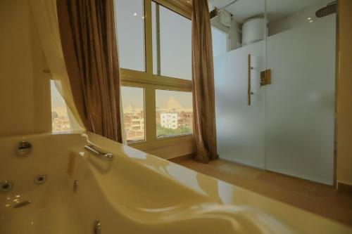 King Khafren View INN في القاهرة: حمام مع حوض كبير ونافذة