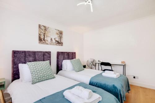 Luxury 5 BDR 2 BA House with Parking in Sandhurst By 360Stays في ساندهيرست: سريرين في غرفة بجدران بيضاء