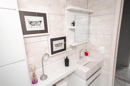 ein weißes Badezimmer mit einem Waschbecken und einem Spiegel in der Unterkunft Amplo e iluminado apto central para temporada in Balneário Camboriú