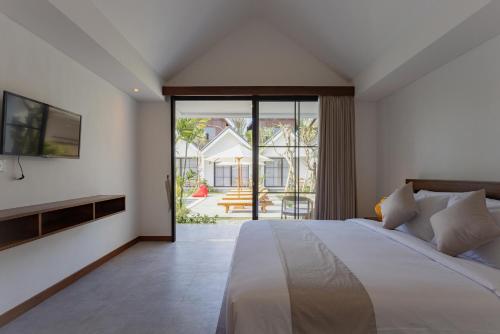 - une chambre avec un grand lit et une porte coulissante en verre dans l'établissement Sari Uma Canggu By Hospitality Bali, à Canggu