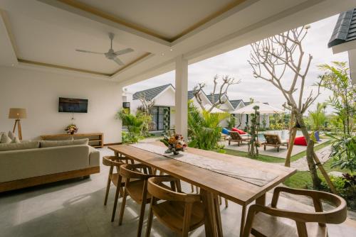 - un salon avec une table et des chaises en bois dans l'établissement Sari Uma Canggu By Hospitality Bali, à Canggu