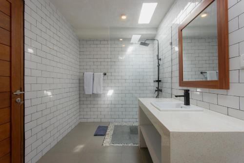 une salle de bains blanche avec un lavabo et un miroir dans l'établissement Sari Uma Canggu By Hospitality Bali, à Canggu