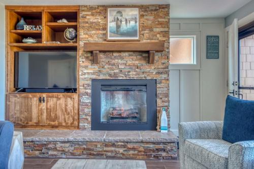 sala de estar con chimenea de ladrillo y TV en Breakers Beach House 10 - Meredith Lodging, en Neskowin