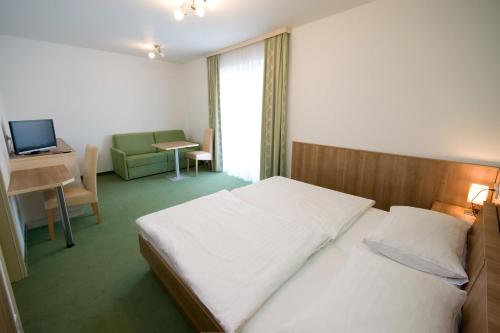 a bedroom with a bed and a desk and a television at Hotel Bauer in Rauchenwarth