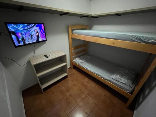 een kleine kamer met 2 stapelbedden en een tv bij Ritz Hostel in Araçatuba