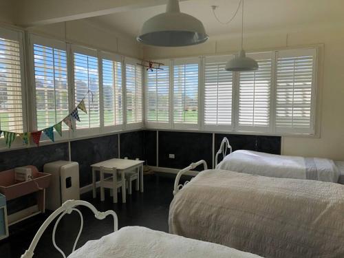 a bedroom with two beds and a table and windows at Trelawney Farm Mudgee - Rural retreat in Mudgee
