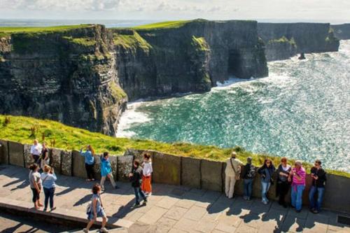 a group of people standing on a wall looking at the ocean at Elegant Lahinch/ Liscannor Cottage 3B 3BR in Liscannor